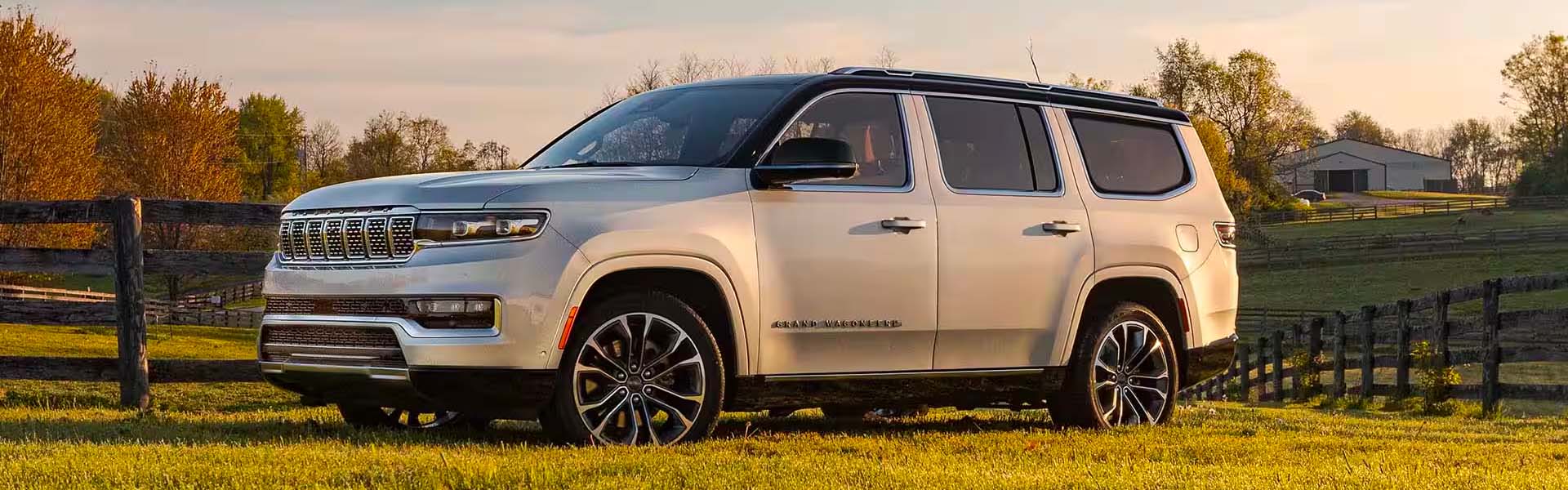 A black 2025 Jeep Grand Wagoneer sitting on some rocks in a forest.