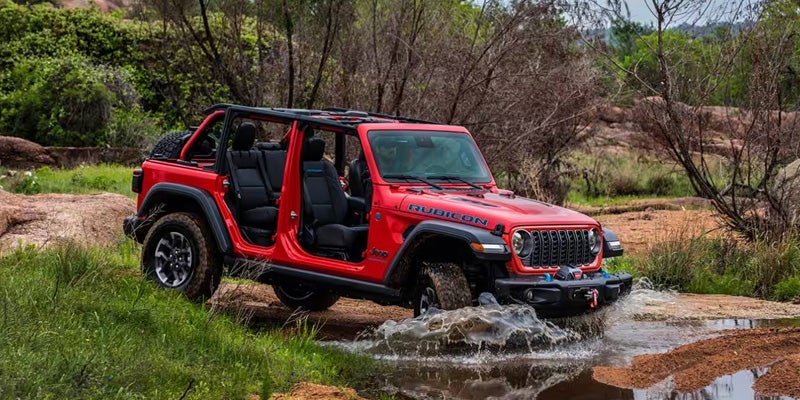 A red jeep driving through some water.