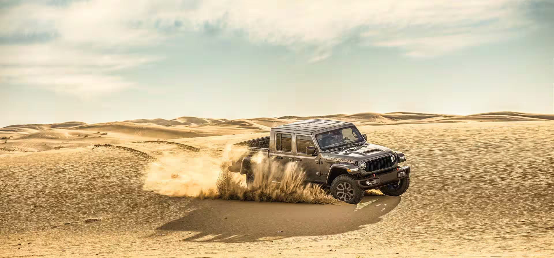 a jeep gladiator driving in the sand