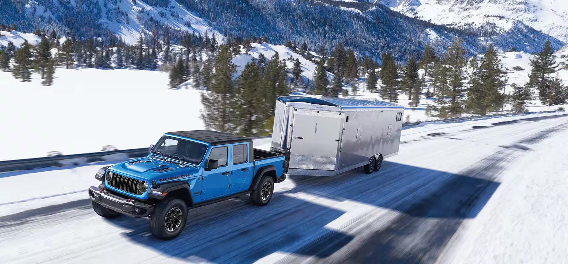 a blue jeep gladiator hauling a silver trailer in the snow