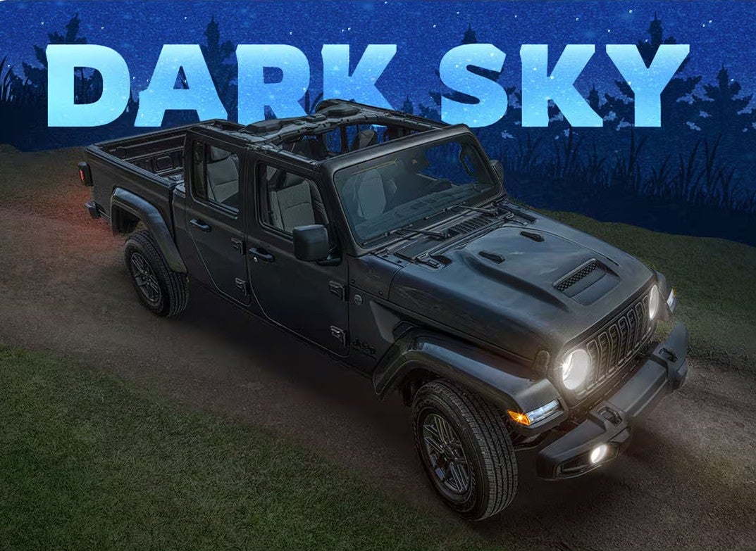 a jeep gladiator with its led headlights on at night with a dark sky text in the background