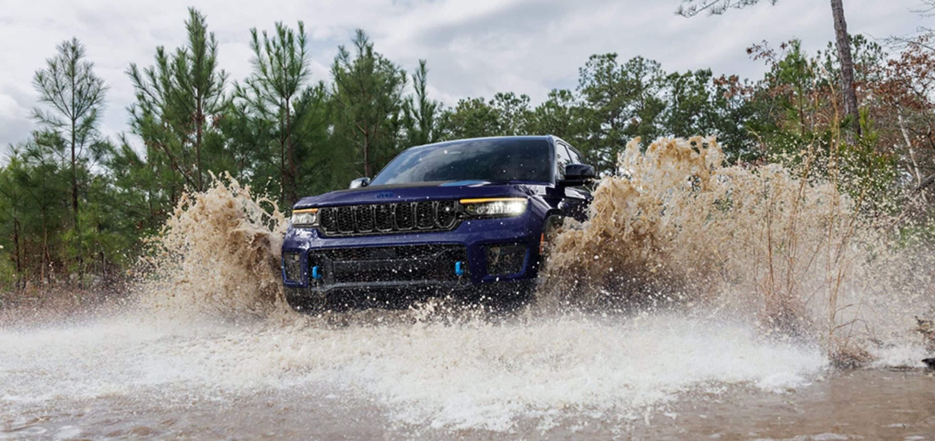 a jeep grand cherokee driving through a creek with water all around