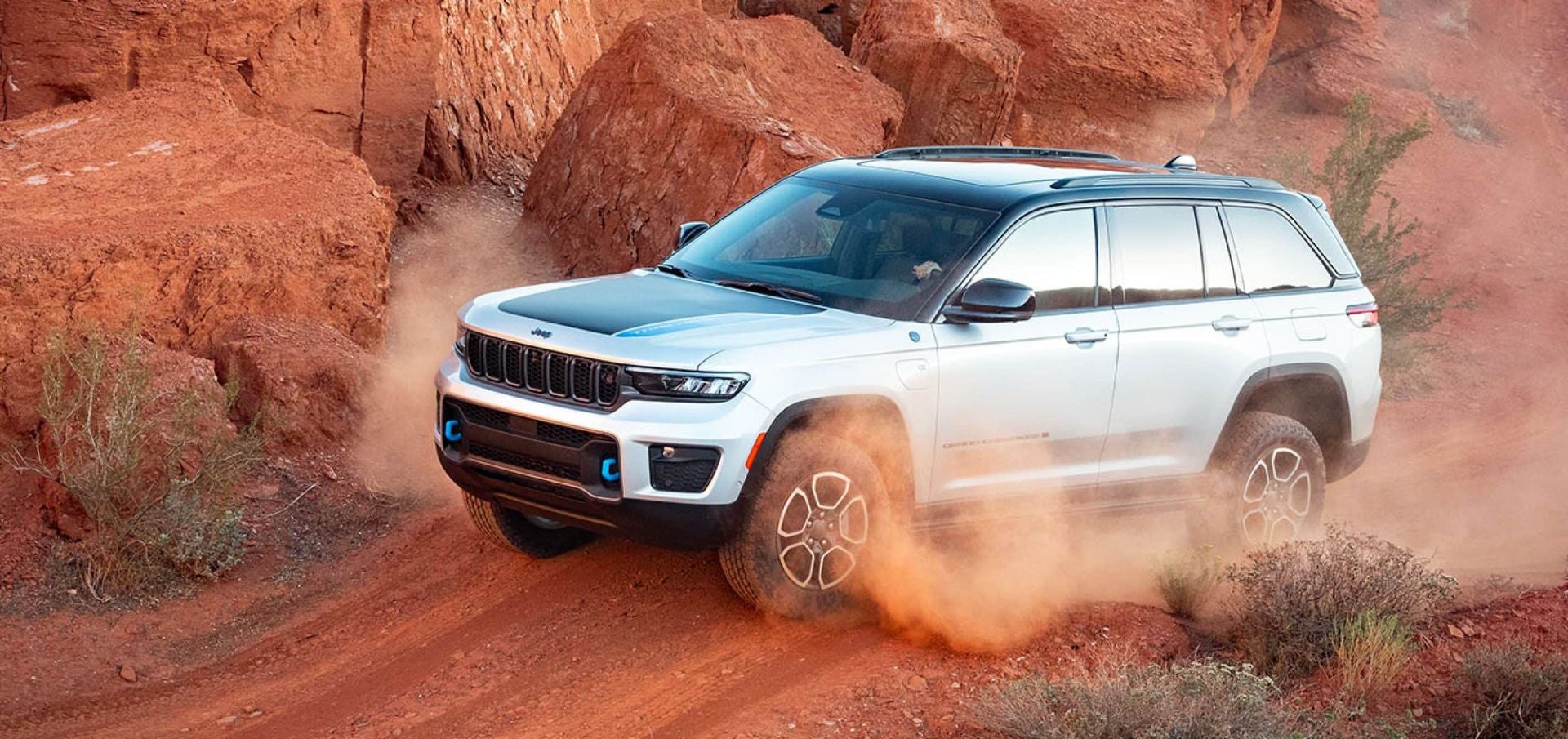 a white jeep grand cherokee driving on a dirt path in the dessert