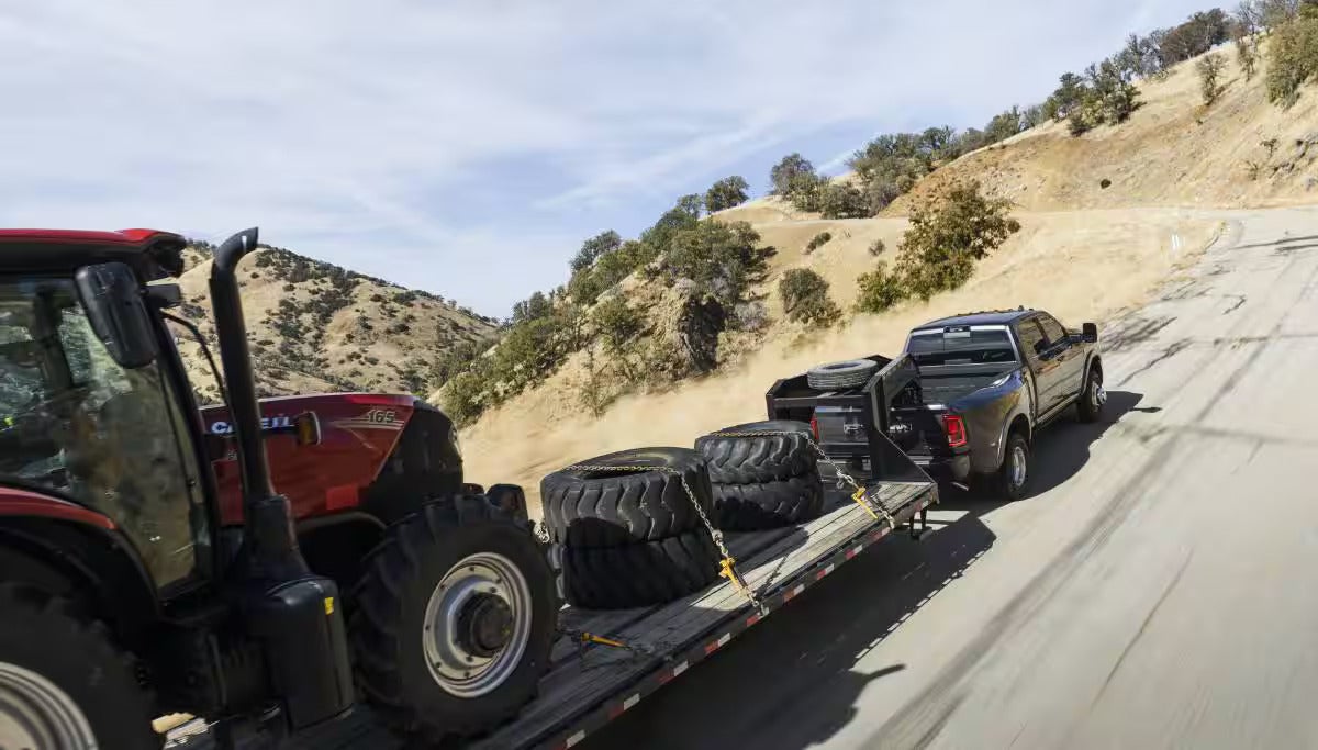 a ram 3500 hauling a tractor and tractor tires on a gooseneck flatbed trailer