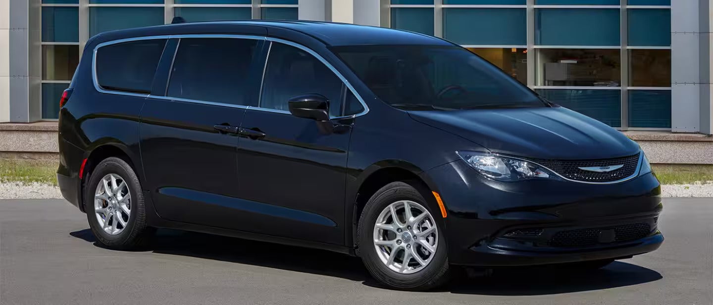 black chrysler voyager parked next to a house