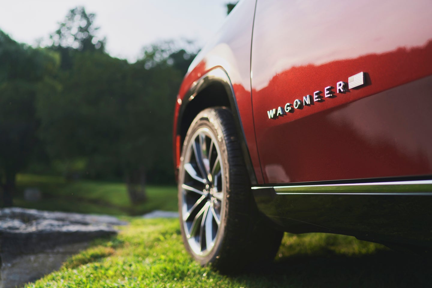 drivers side exterior close up of the wheel and wagoneer emblem on a dark red 2025 jeep wagoneer