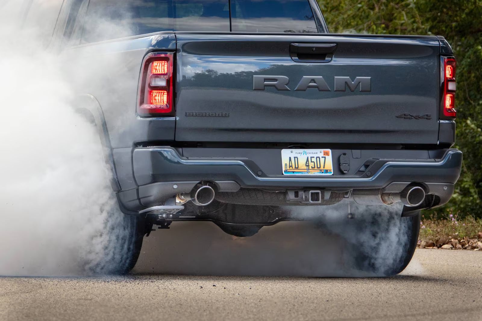 a dark ram 1500 peeling out in a parking lot with white smoke coming from the wheels.