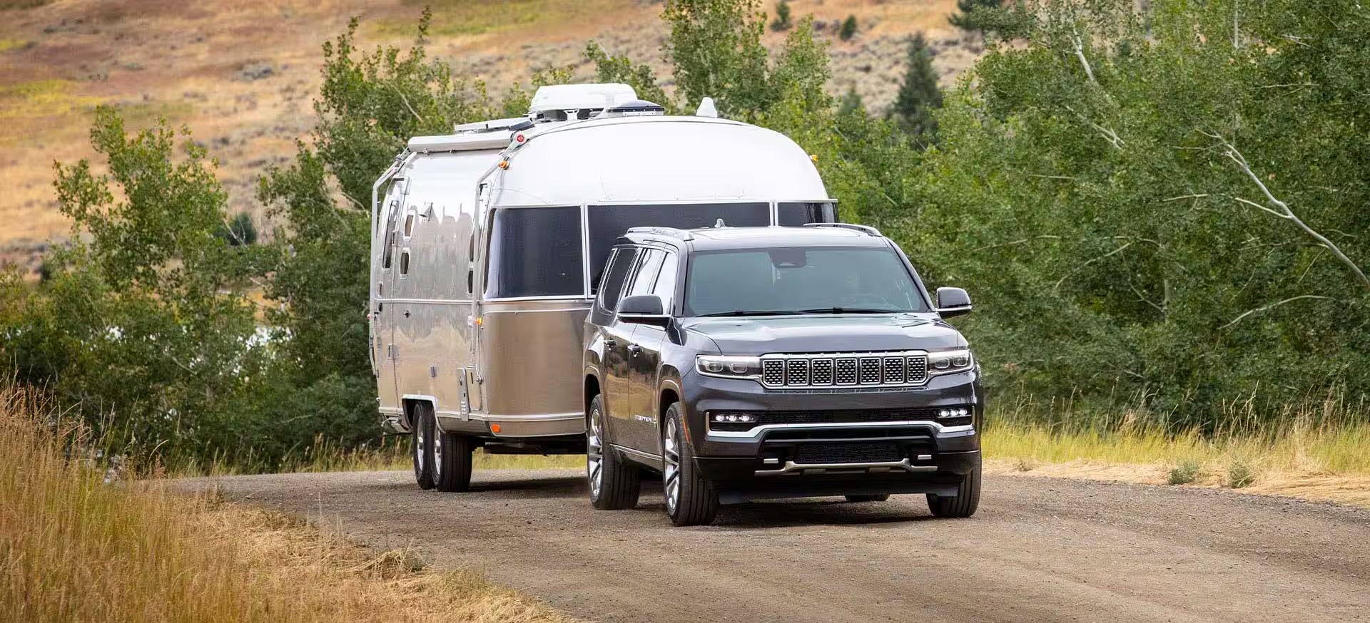 A 2025 white Jeep Grand Wagoneer towing an airline RV.