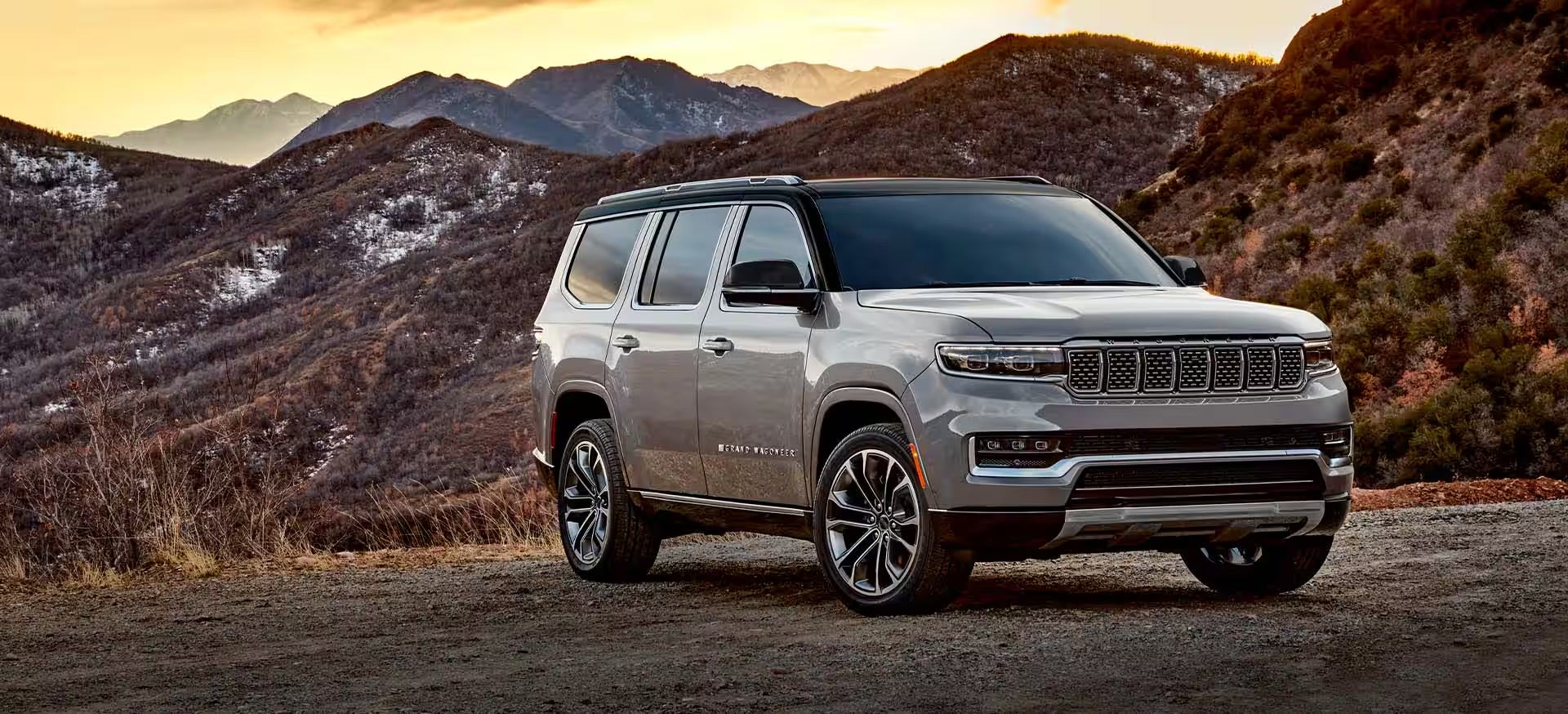 A 2025 white Jeep Grand Wagoneer parked on the mountains during a sunset.