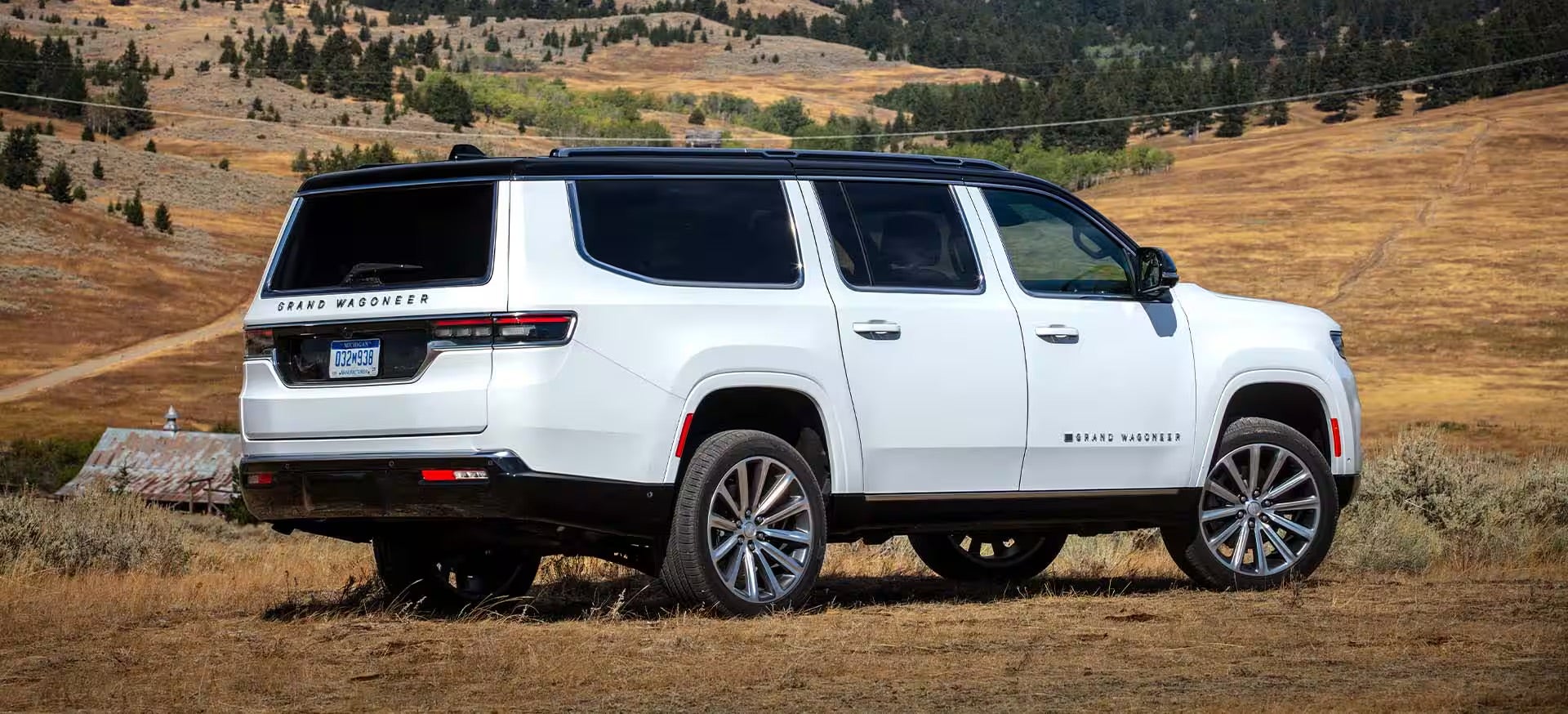 A white 2025 Jeep Grand Wagoneer parked in a field on a sunny day.