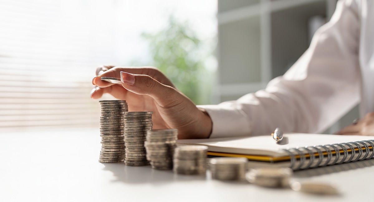 a person with quarters stacked and a piece of paper on a table